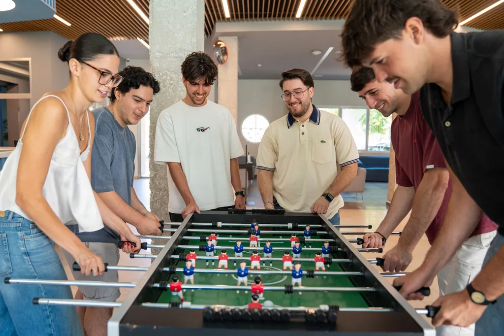 Grupo de jóvenes jugando al futbolín en la zona de ocio de la residencia